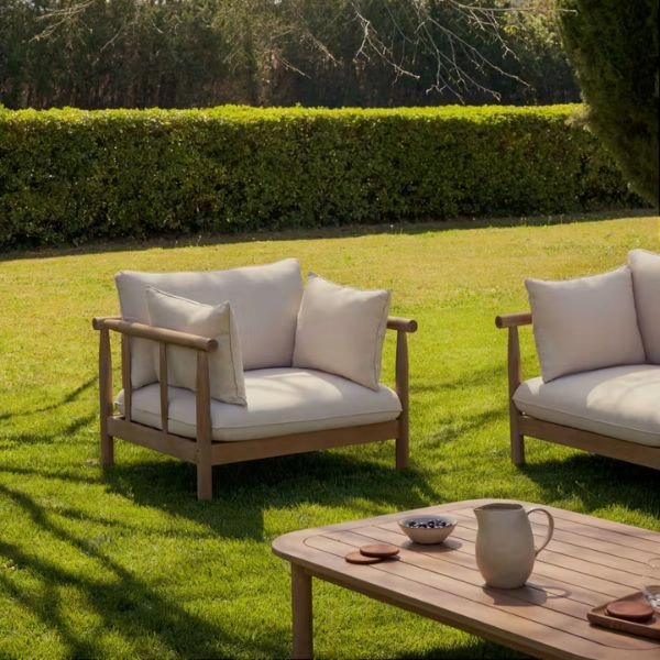 Ξύλινες πολυθρόνες κήπου με μαξιλάρια τοποθετημένες πάνω σε γκαζόν