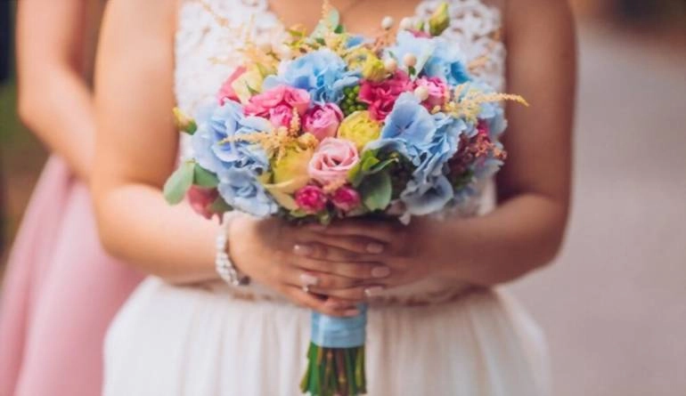 Νύφη με λουλούδια στο χέρι σε εξωτερικούς χώρους.