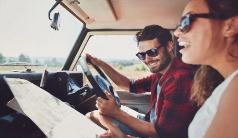 Επέτειος γάμου: 9 ιδέες για να γιορτάσετε την αγάπη σας 5 Ευτυχισμένο νεαρό ζευγάρι με χάρτη στο αυτοκίνητο.