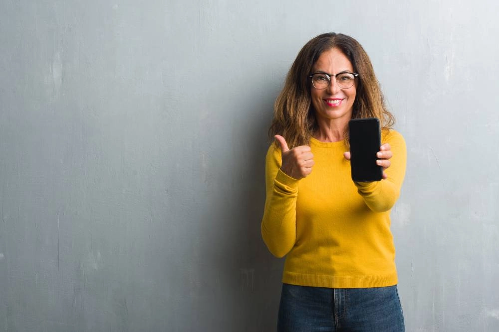 χαρούμενη κοπέλα κρατάει κινητό τηλέφωνο