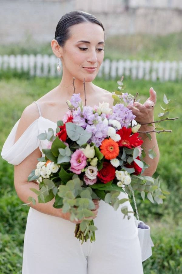 Όμορφη νύφη κρατά την πολύχρωμη γαμήλια ανθοδέσμη της.