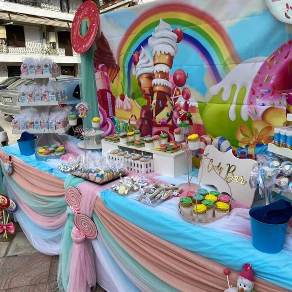 Πολύχρωμη διακόσμηση βάπτισης με θέμα τη χώρα των ζαχαρωτών, με παστέλ μπαλόνια, γλυκά, και παιχνιδιάρικα διακοσμητικά.