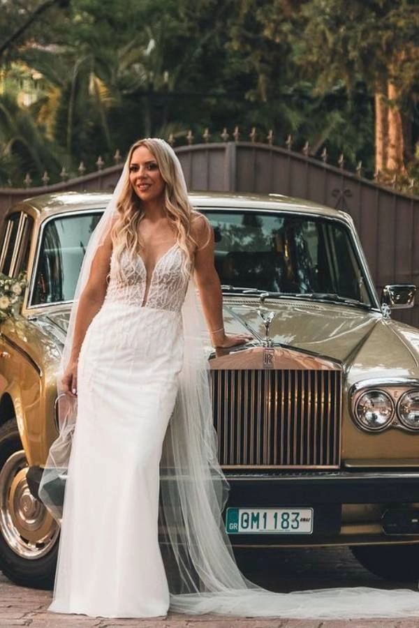 Γάμος 2025: 10+ τάσεις που θα λατρέψουν οι μέλλουσες νύφες 12 Νύφη με λευκό νυφικό στέκεται μπροστά σε χρυσό κλασικό Rolls Royce διακοσμημένο με λουλούδια