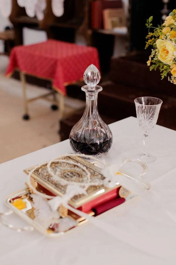 Έξοδα κουμπάρου και υποχρεώσεις | Τι πληρώνει στο γάμο; 7 Σετ γάμου με επάργυρο δίσκο, καράφα με κόκκινο κρασί, ποτήρι και στέφανα πάνω σε τραπέζι εκκλησίας