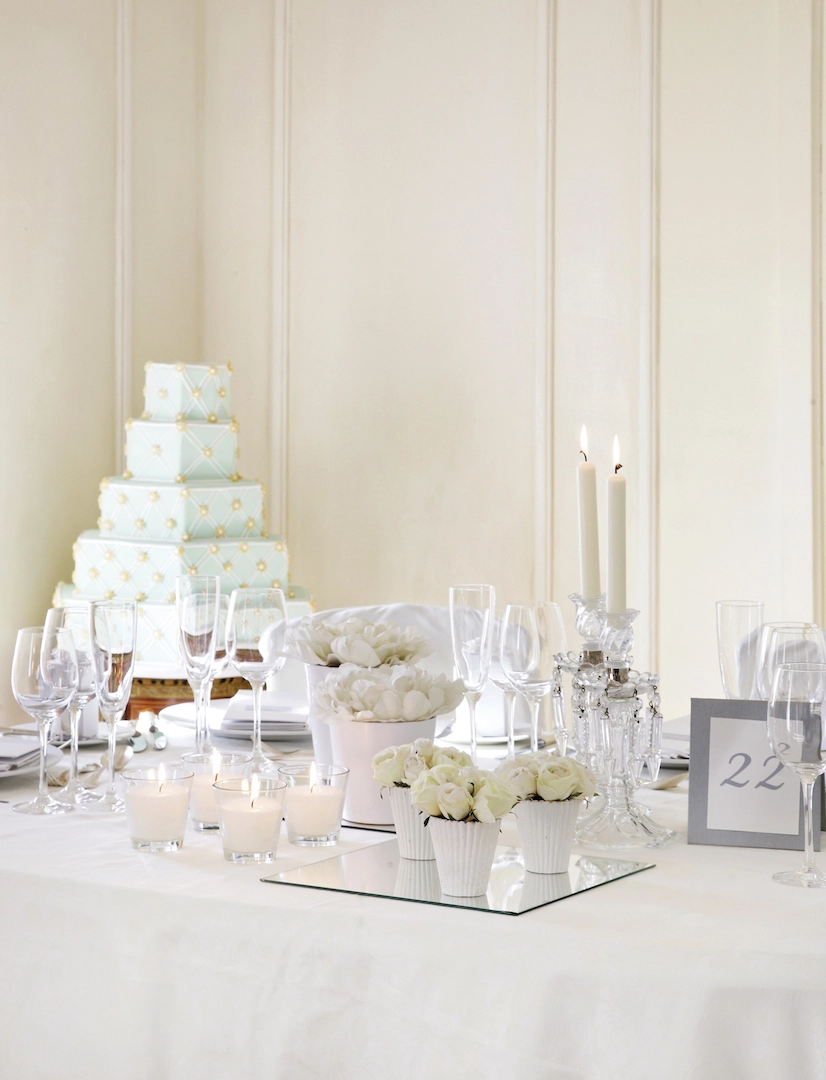 Elegant διακόσμηση τραπεζιού γάμου με λευκά λουλούδια, κεριά και γαμήλια τούρτα σε παστέλ μπλε, από τη Vassiliki Creations στο King George Athens