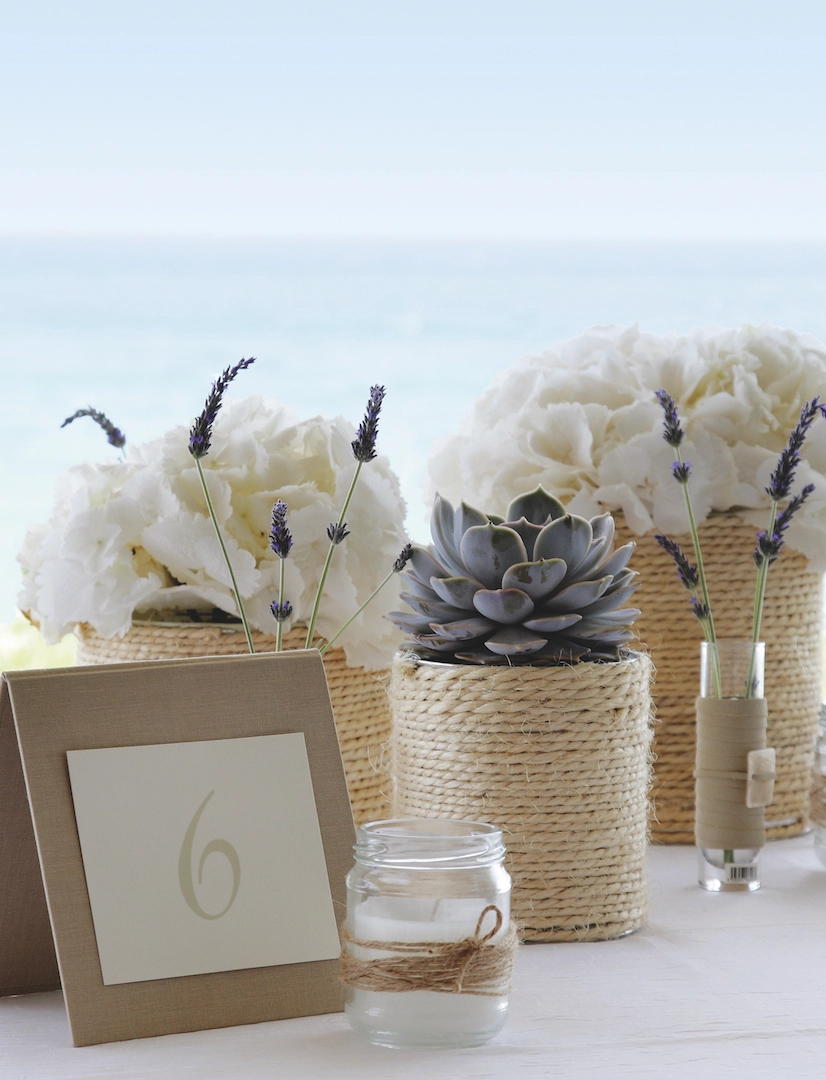 Boho διακόσμηση τραπεζιού γάμου με λευκά άνθη, λεβάντα και παχύφυτα σε νησιώτικο σκηνικό δίπλα στη θάλασσα, από τη Vassiliki Creations