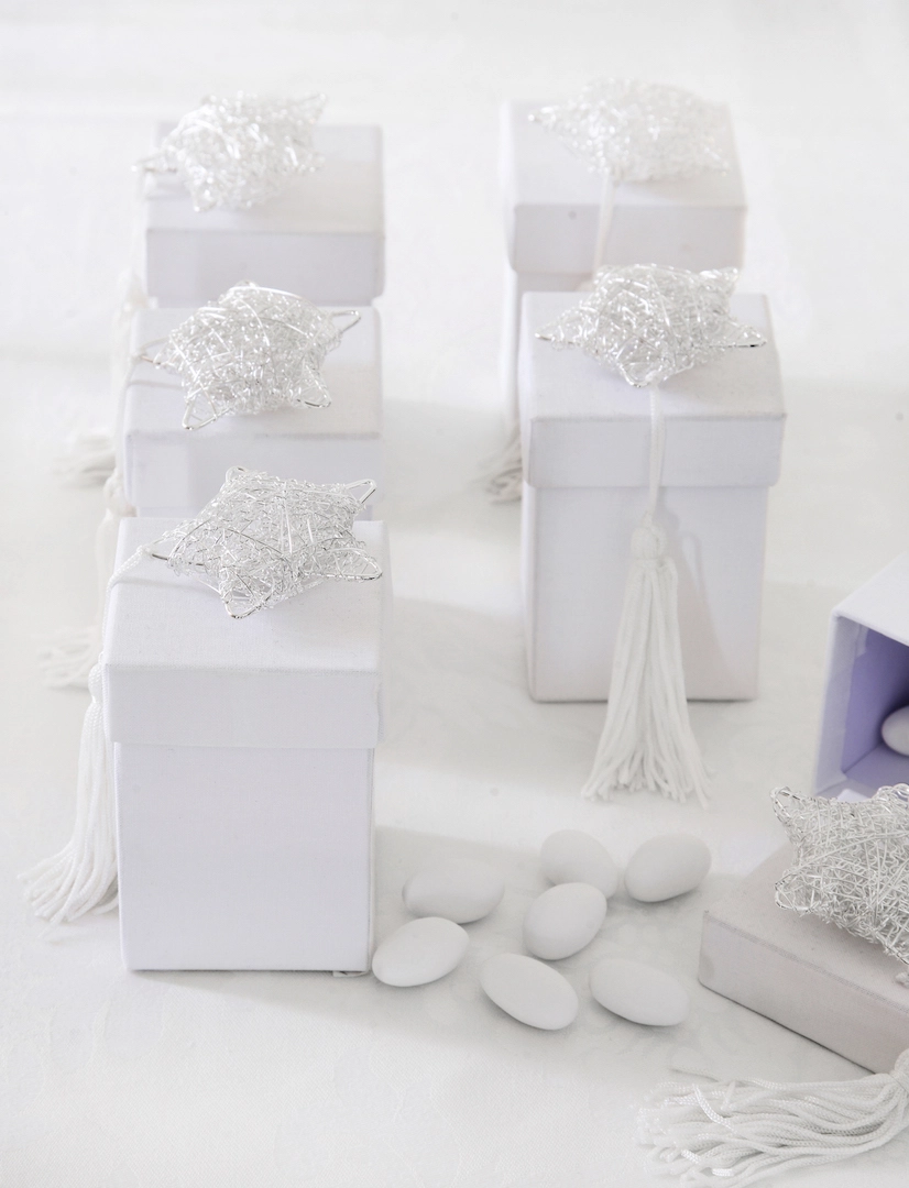 Λευκές μπομπονιέρες γάμου σε κουτάκια με ασημένια αστέρια και λευκή φούντα, τοποθετημένες σε elegant τραπέζι δεξίωσης, από τη Vassiliki Creations στο King George