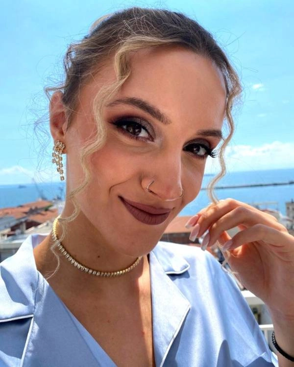 Καλεσμένη με φυσικό μακιγιάζ και nude κραγιόν σε γάμο με φόντο θάλασσα