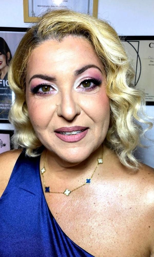 Γυναίκα με ξανθά μαλλιά και ροζ-μωβ μακιγιάζ ματιών, ντυμένη επίσημα για γάμο