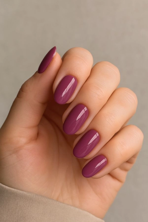 Νύχια για γάμο: Ιδέες για καλεσμένη κουμπάρα και πεθερά 9 Κοντινό σε χέρι καλεσμένης με γυαλιστερό mauve μανικιούρ σε ουδέτερο φόντο, κομψή επιλογή για νύχια για γάμο.