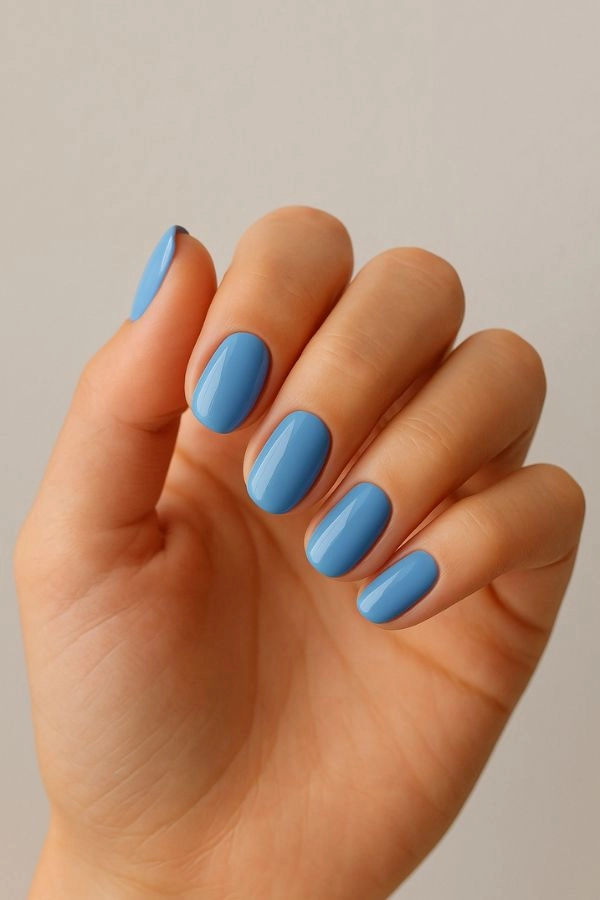 Νύχια για γάμο: Ιδέες για καλεσμένη κουμπάρα και πεθερά 12 Κοντινό σε χέρι καλεσμένης με παστέλ μπλε γυαλιστερό μανικιούρ σε ουδέτερο φόντο, κομψή ιδέα για νύχια για γάμο.