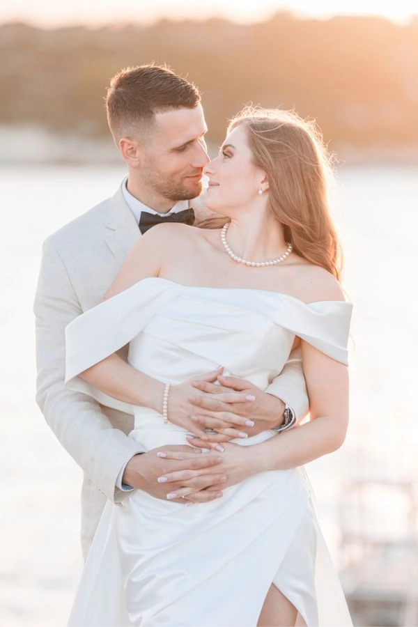 Νεόνυμφο ζευγάρι αγκαλιασμένο σε ρομαντικό φως την ώρα του ηλιοβασιλέματος